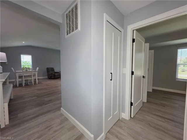 Hallway featuring plenty of natural light, wood finished floors, and vaulted ceiling