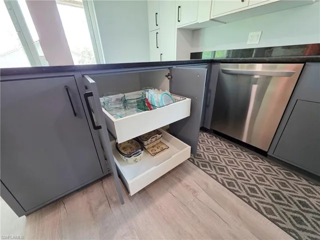 Kitchen with dishwasher, dark countertops, and light wood-style flooring