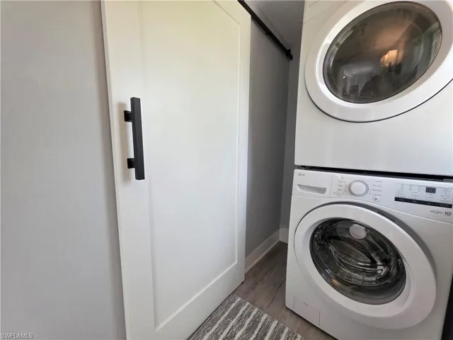 Washroom featuring stacked washer / drying machine and wood finished floors