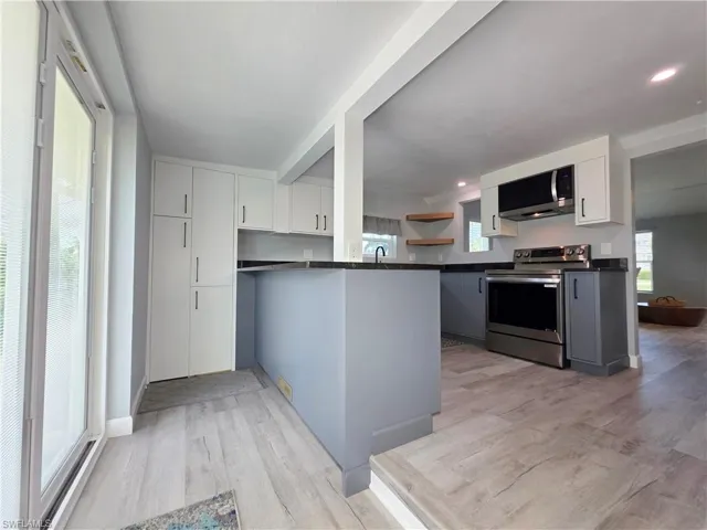 Kitchen featuring dark countertops, appliances with stainless steel finishes, light wood-type flooring, and a peninsula