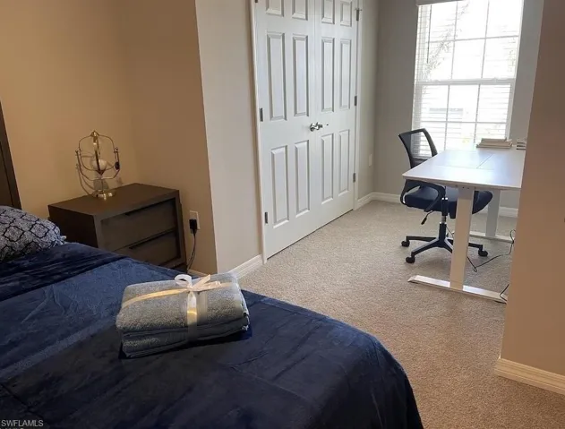 Carpeted bedroom with baseboards and an office area