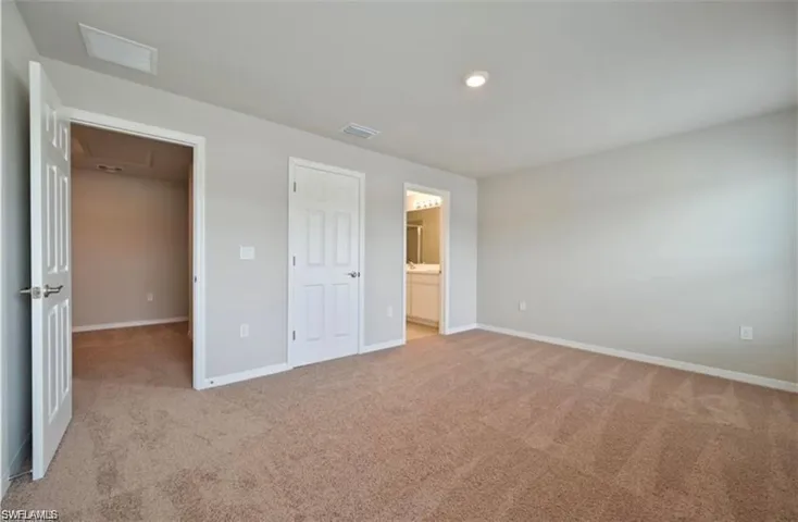 Unfurnished bedroom featuring light carpet, ensuite bath, and recessed lighting