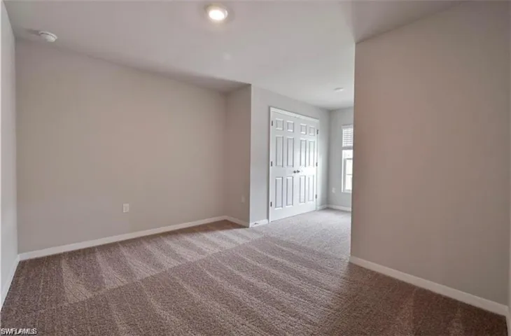 Carpeted spare room featuring baseboards and a smoke detector
