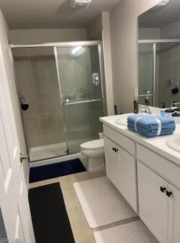 Full bathroom with tile patterned flooring, double vanity, and a shower stall