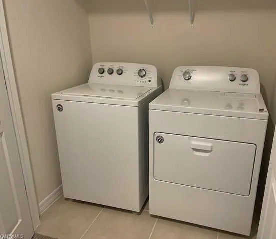 Laundry area featuring washer and clothes dryer and light tile patterned flooring