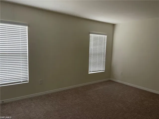 Carpeted spare room featuring baseboards