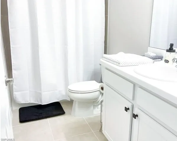 Bathroom with vanity, tile patterned floors, and a shower with shower curtain