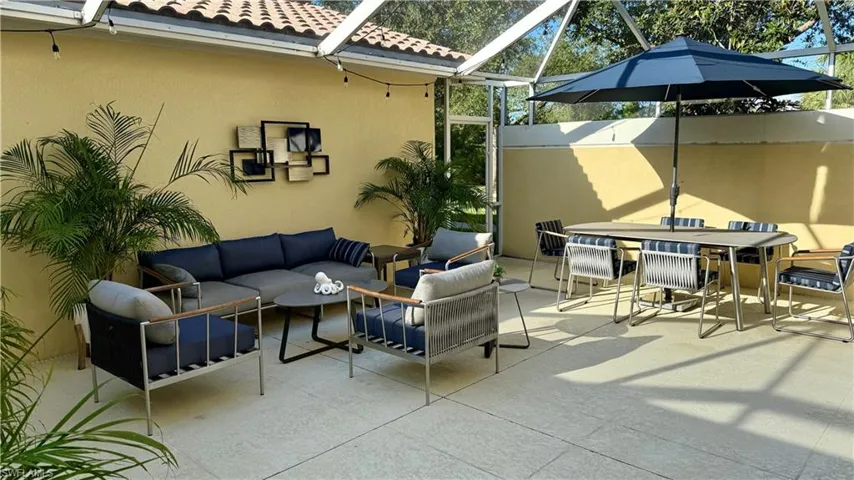 This outdoor living area features a tiled patio, a screened enclosure, and a decorative wall accent