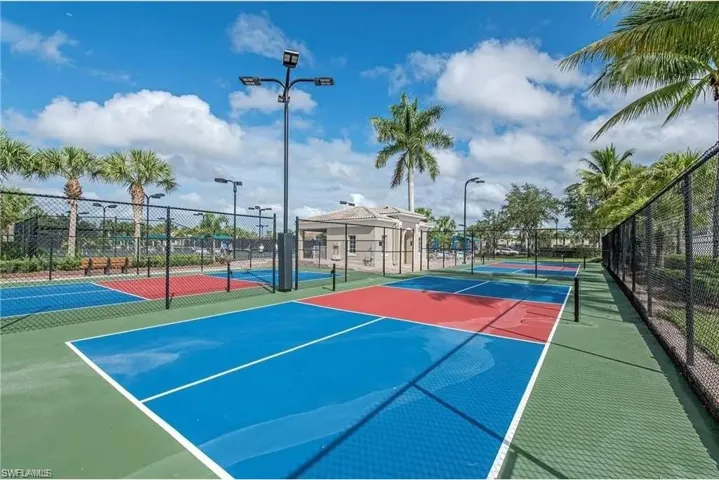 The property offers well-maintained sports courts, featuring vibrant blue and red surfaces, enclosed by black chain-link fencing