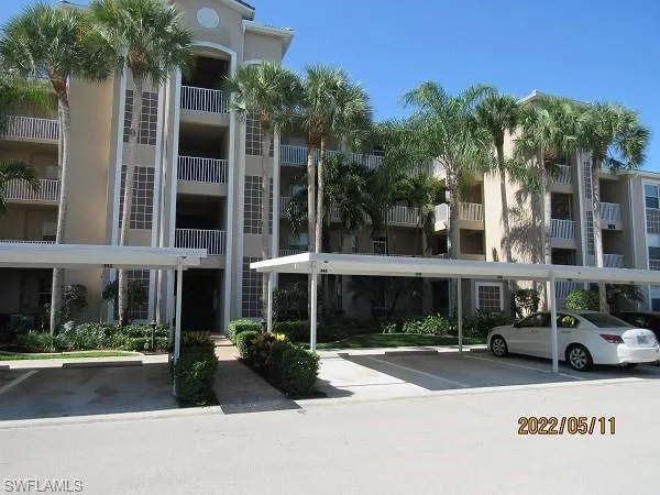 View of apartment building / complex featuring covered parking