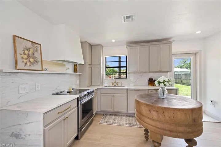 Kitchen featuring decorative backsplash, gray cabinets, light wood-style flooring, recessed lighting, and wall chimney range hood