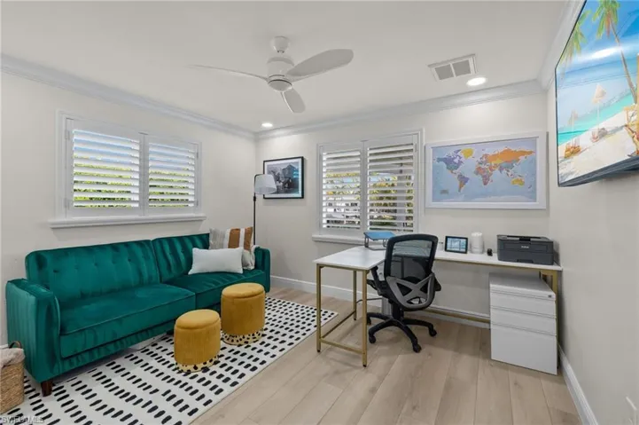 Office with light wood-type flooring, ceiling fan, ornamental molding, and a healthy amount of sunlight