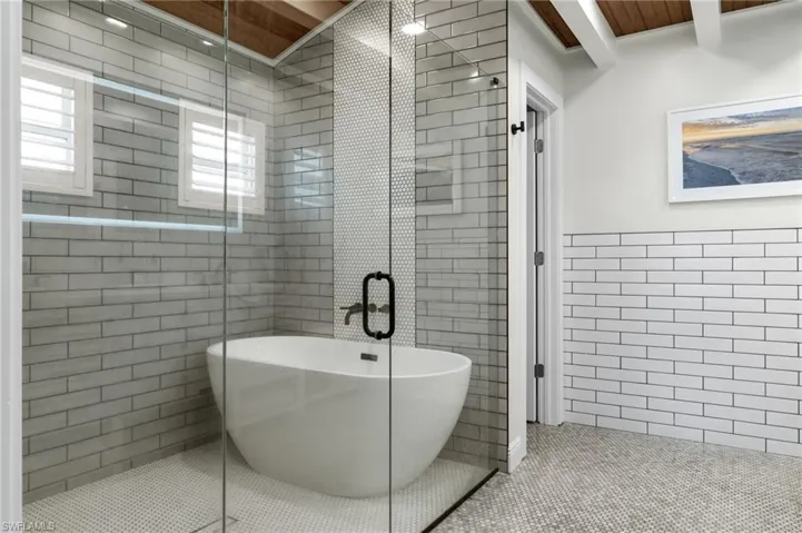 Full bathroom with tile walls, a freestanding tub, tile patterned flooring, and a stall shower