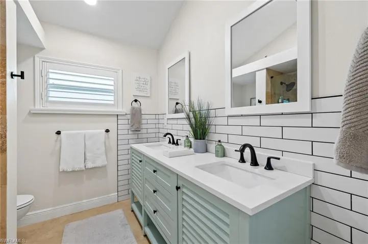 Bathroom with a sink, tiled shower, and vaulted ceiling