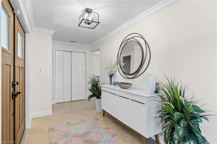 Foyer entrance with baseboards, crown molding, light tile patterned floors, and an inviting chandelier