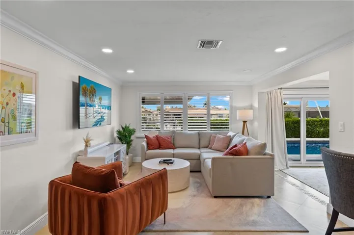 Tiled living room with recessed lighting, crown molding, baseboards, and visible vents