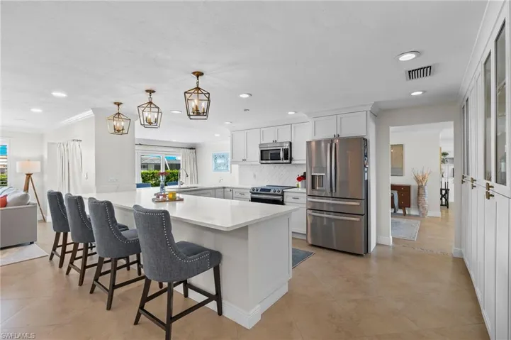 Kitchen featuring a breakfast bar area, tasteful backsplash, appliances with stainless steel finishes, a peninsula, and visible vents