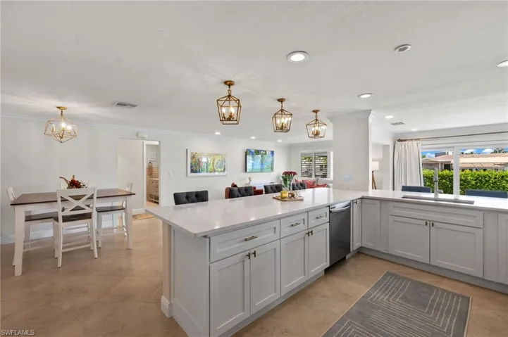 Kitchen with a sink, stainless steel dishwasher, plenty of natural light, visible vents, and an inviting chandelier