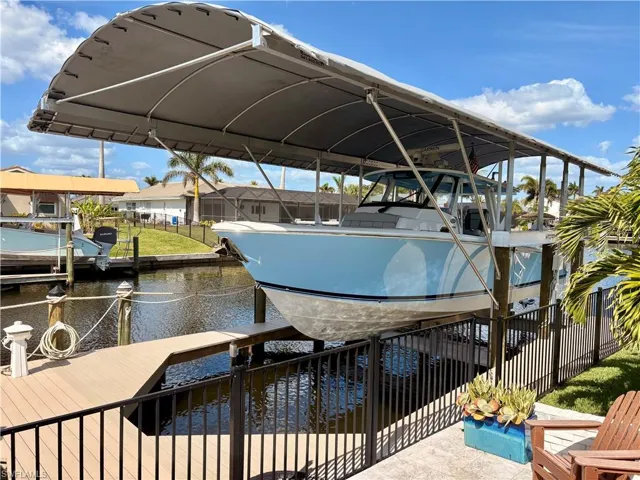 View of dock featuring a water view, fence, and boat lift