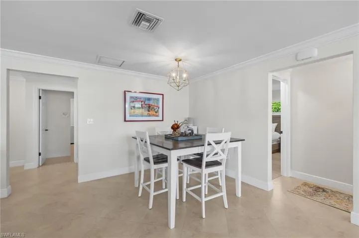 Dining area featuring baseboards, visible vents, crown molding, and an inviting chandelier