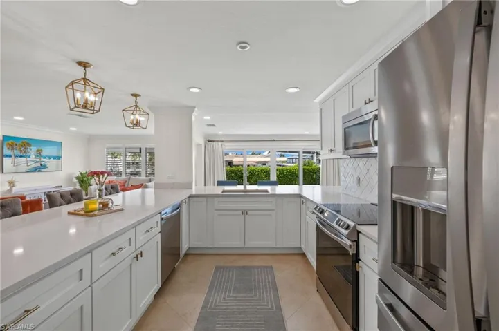 Kitchen featuring light tile patterned flooring, crown molding, stainless steel appliances, a sink, and open floor plan
