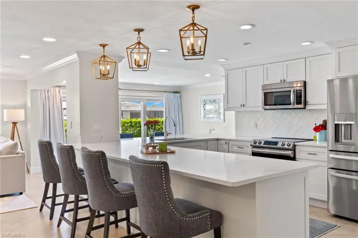 Kitchen featuring ornamental molding, a sink, a peninsula, a notable chandelier, and appliances with stainless steel finishes