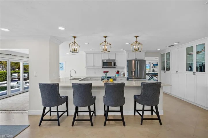 Kitchen with backsplash, a sink, a breakfast bar area, stainless steel appliances, and an inviting chandelier
