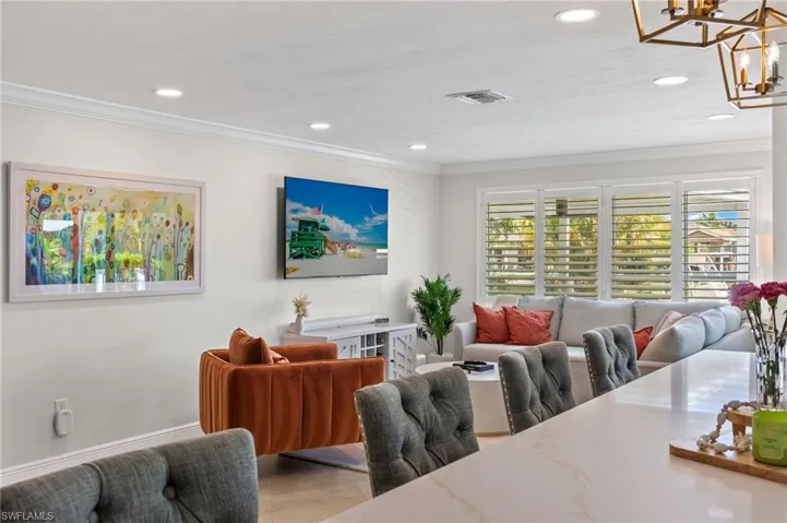 Living area featuring baseboards, visible vents, ornamental molding, recessed lighting, and an inviting chandelier