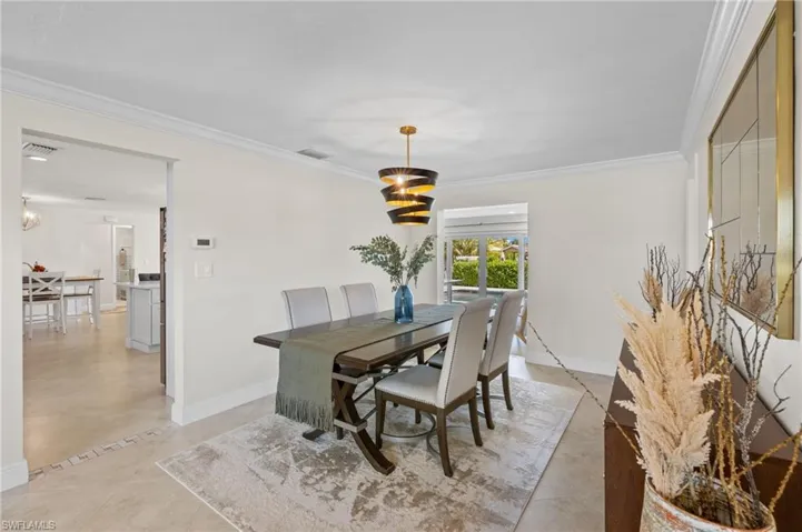 Dining area with baseboards, visible vents, and crown molding