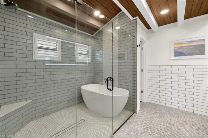 Bathroom featuring tile patterned flooring, tile walls, wooden ceiling, a shower stall, and beamed ceiling