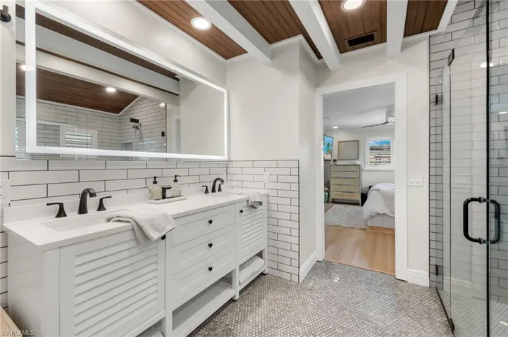 Ensuite bathroom featuring tile walls, recessed lighting, a sink, a stall shower, and ensuite bathroom