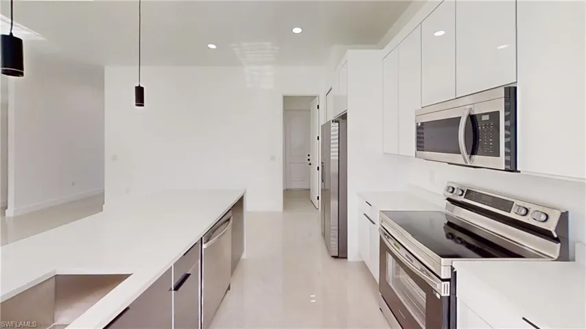 Kitchen featuring stainless steel appliances, modern cabinets, decorative light fixtures, and white cabinets