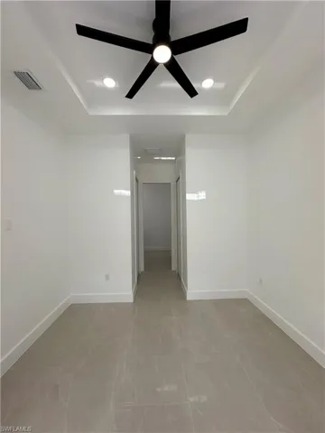 Empty room featuring a raised ceiling, ceiling fan, and recessed lighting
