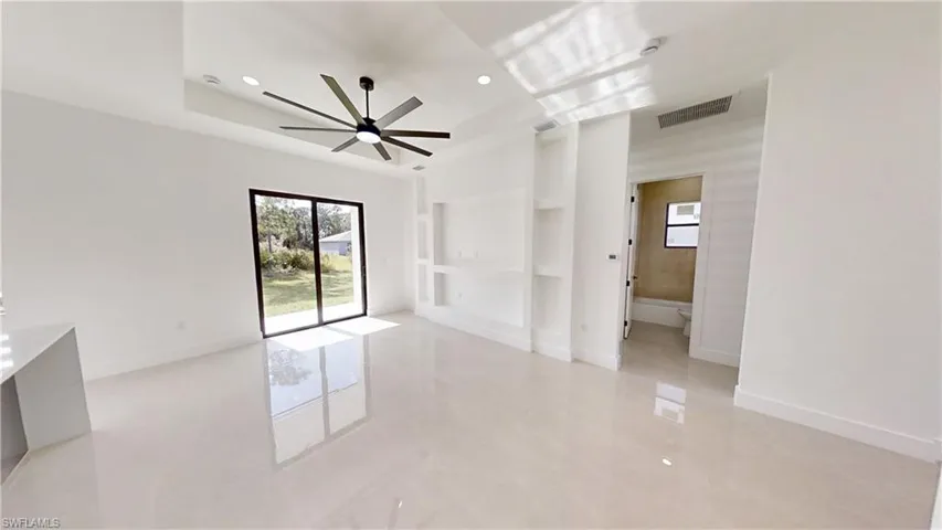 Empty room with ceiling fan, built in shelves, and recessed lighting