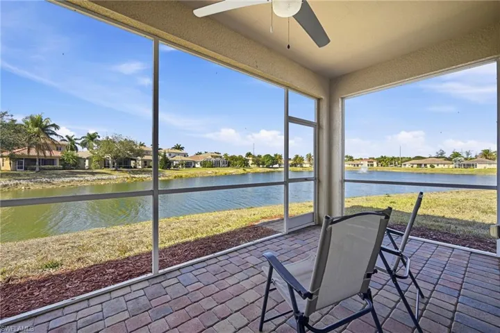Sunroom / solarium featuring a residential view, ceiling fan, and a water view