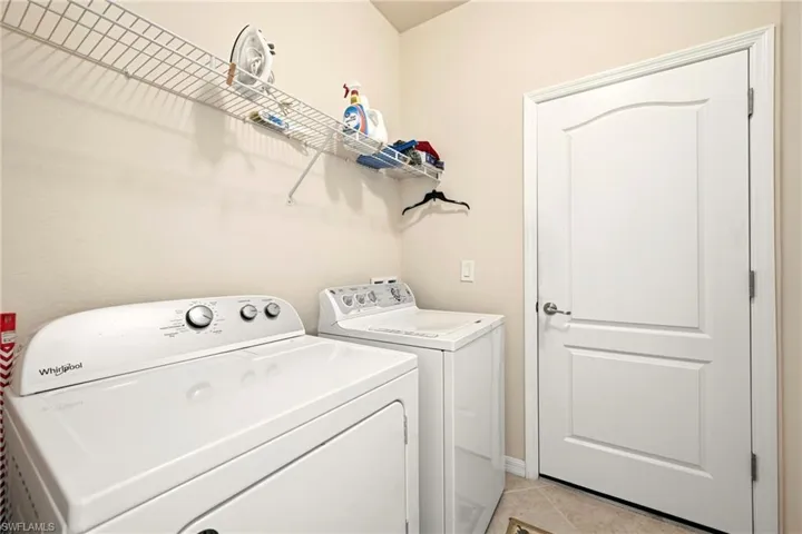 Laundry area with light tile patterned flooring and washer and clothes dryer