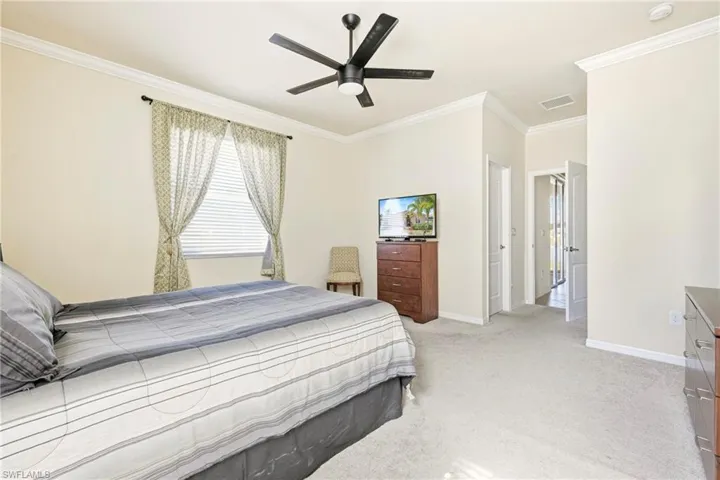 Bedroom with crown molding, light colored carpet, and a ceiling fan