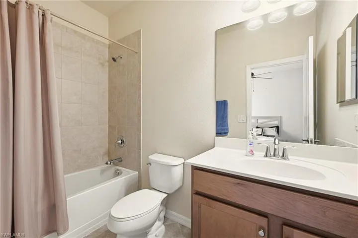 Bathroom with vanity, shower / bath combo, and a textured wall