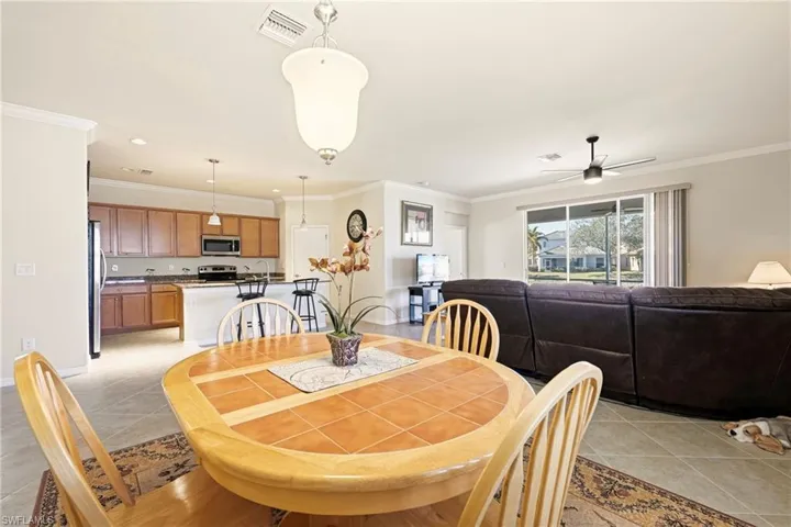 Dining space featuring light tile patterned floors, crown molding, and a ceiling fan