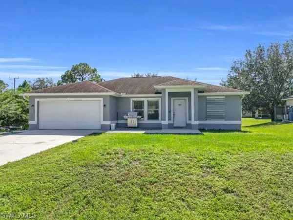 Ranch-style house with stucco siding, driveway, a garage, and a front lawn