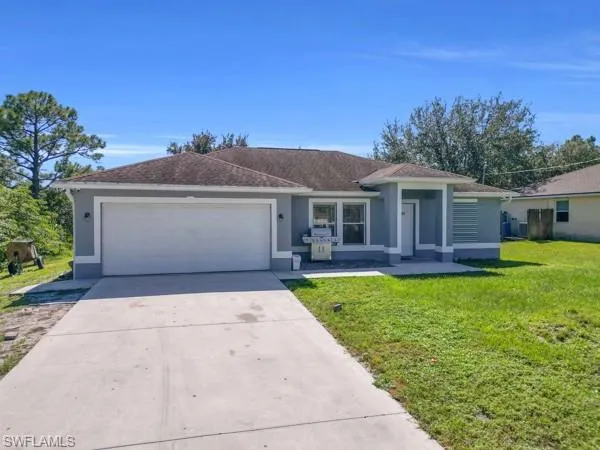 Single story home with stucco siding, a front yard, driveway, and a garage