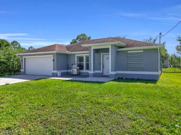 Ranch-style house featuring stucco siding, a front yard, driveway, and a garage