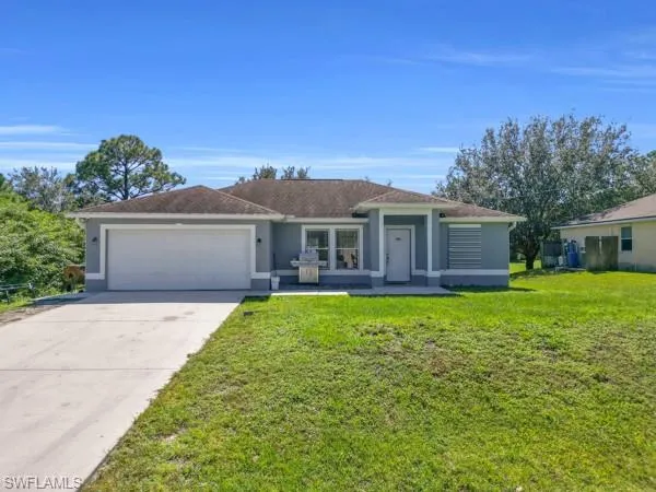 Single story home featuring a front lawn, stucco siding, concrete driveway, and a garage