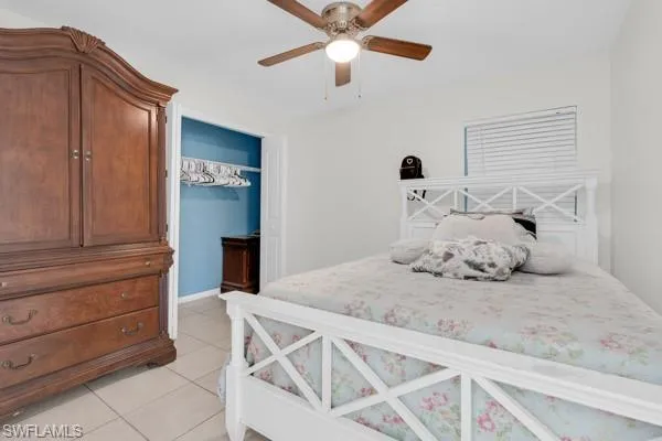 Bedroom with light tile patterned floors, a closet, and a ceiling fan