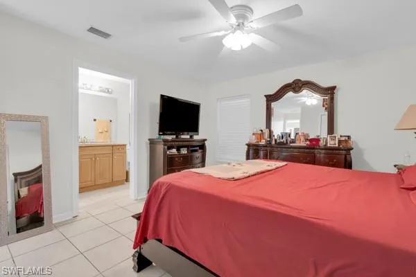 Bedroom featuring light tile patterned floors, a ceiling fan, and ensuite bathroom