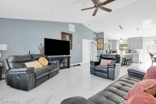 Living room featuring marble tiled flooring, lofted ceiling, and ceiling fan