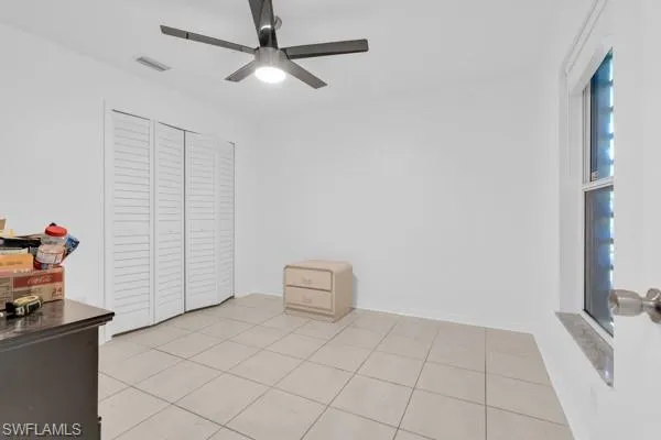 Bedroom with ceiling fan, light tile patterned floors, and a closet