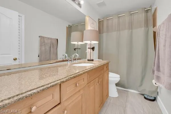 Bathroom with vanity, shower / bath combo, and light tile patterned floors