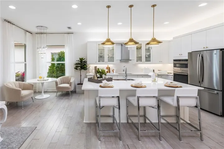 Kitchen featuring a breakfast bar area, sink, stainless steel appliances, and wall chimney range hood