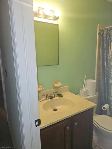 Bathroom with vanity, curtained shower, and toilet